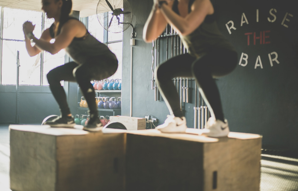 Two women working out with box jumps at a fitness studio